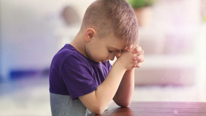 little boy praying with folded hands